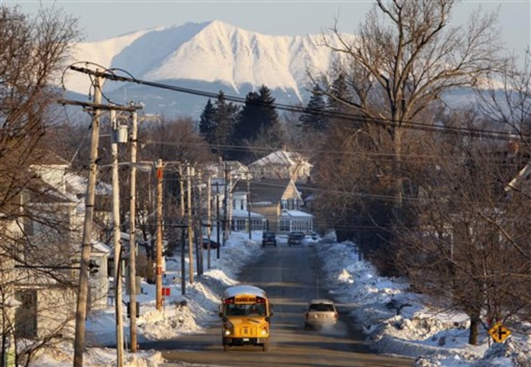 FILE - In this Wednesday, March 9, 2011 file photo, Mount Katahdin rises in the background as a school bus makes its rounds in Millinocket, Maine. The town's public high school is touting its natural resources and it's proximity to Katahdin, in it's effort to recruit students from China to help boost enrollment and revenues. But only six Chinese students will attend high school in fall 2011 after the school district's recruitment effort fell far short of its enrollment goal of 60. (AP Photo/Robert F. Bukaty, File)